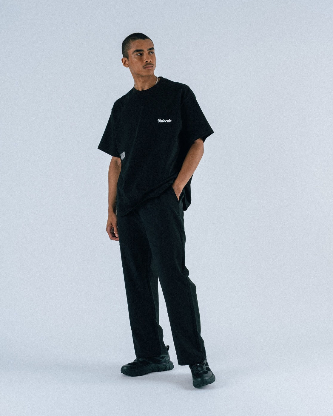 Person wearing a black t-shirt and pants with a brand logo on a white background
