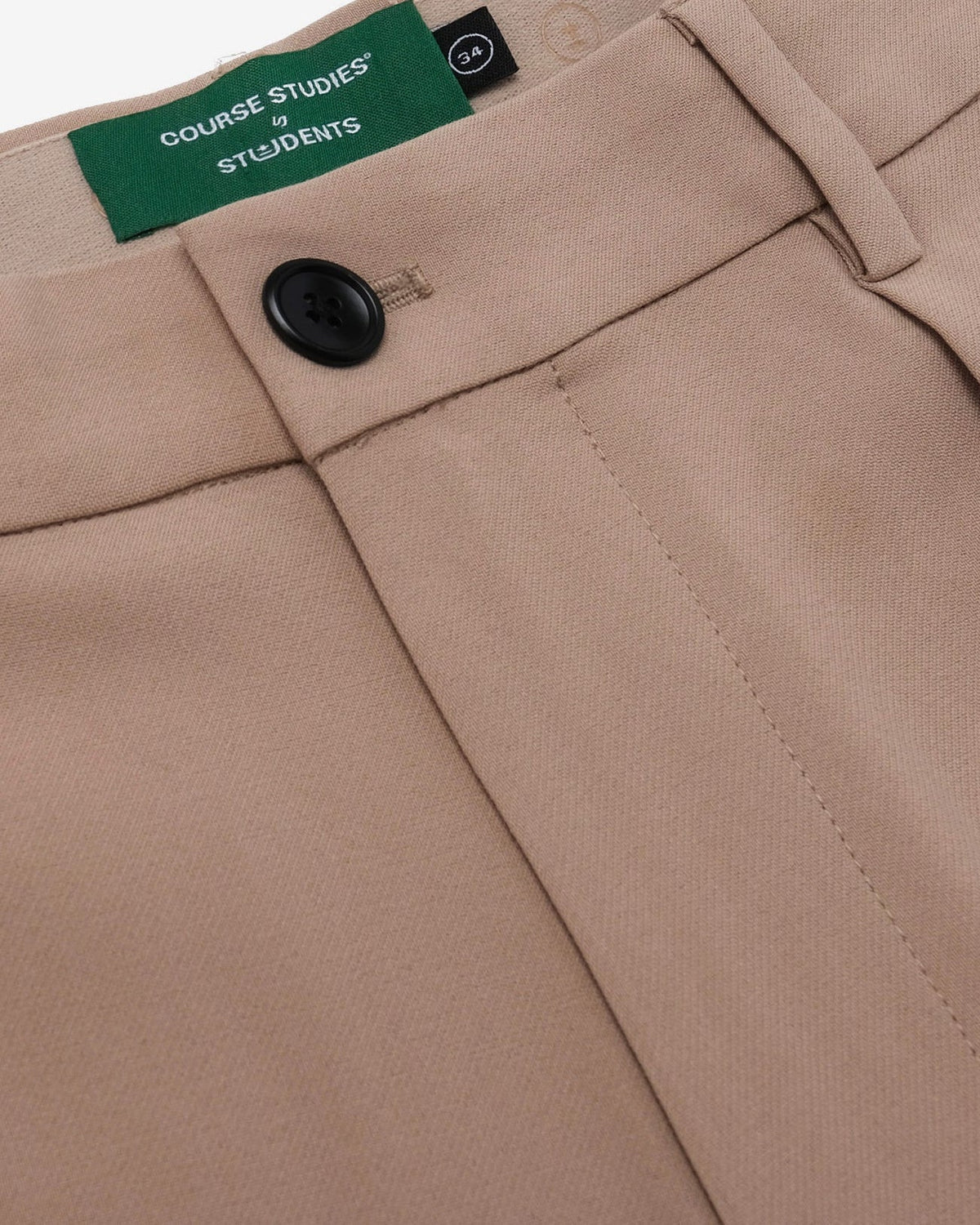 Close-up of beige pants with a button and 'Course Studies by Students' label.