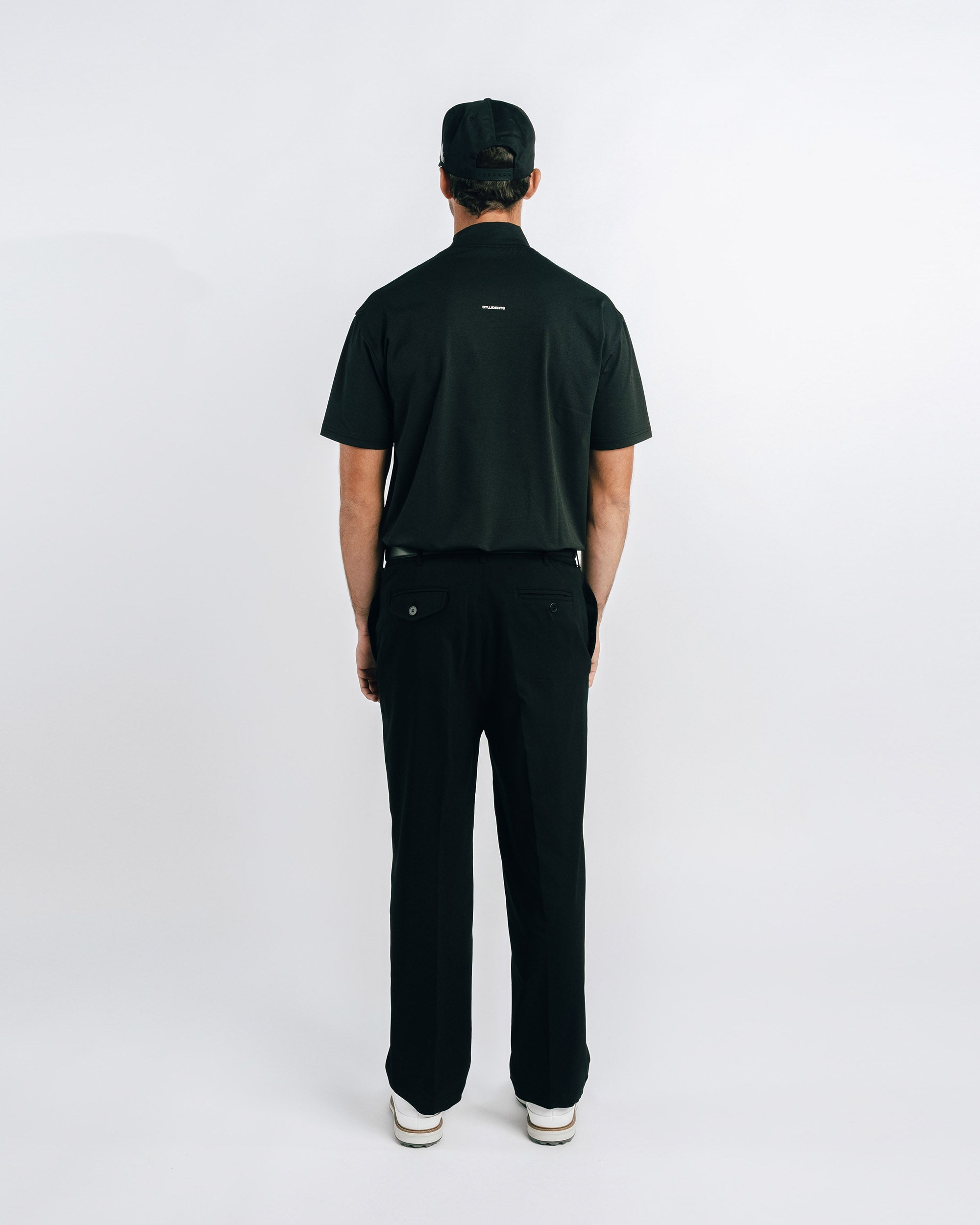 Person wearing a black polo shirt and pants on a white background
