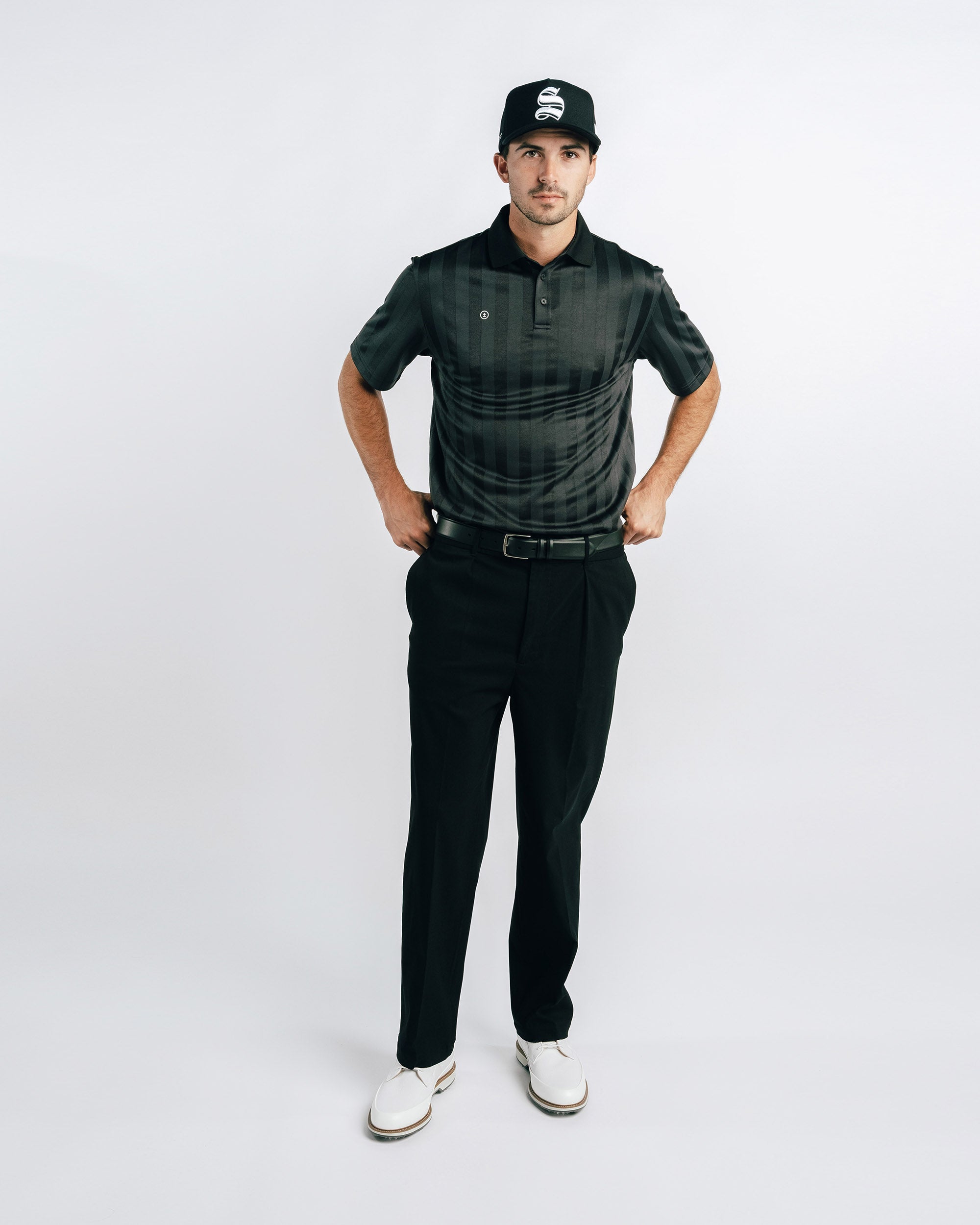 Man wearing a black outfit with a cap on a white background