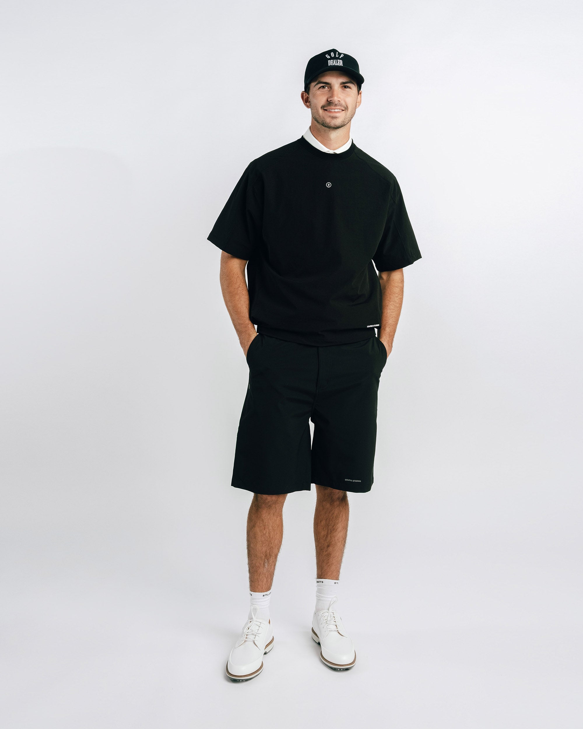 Man wearing a black outfit with a cap on a white background