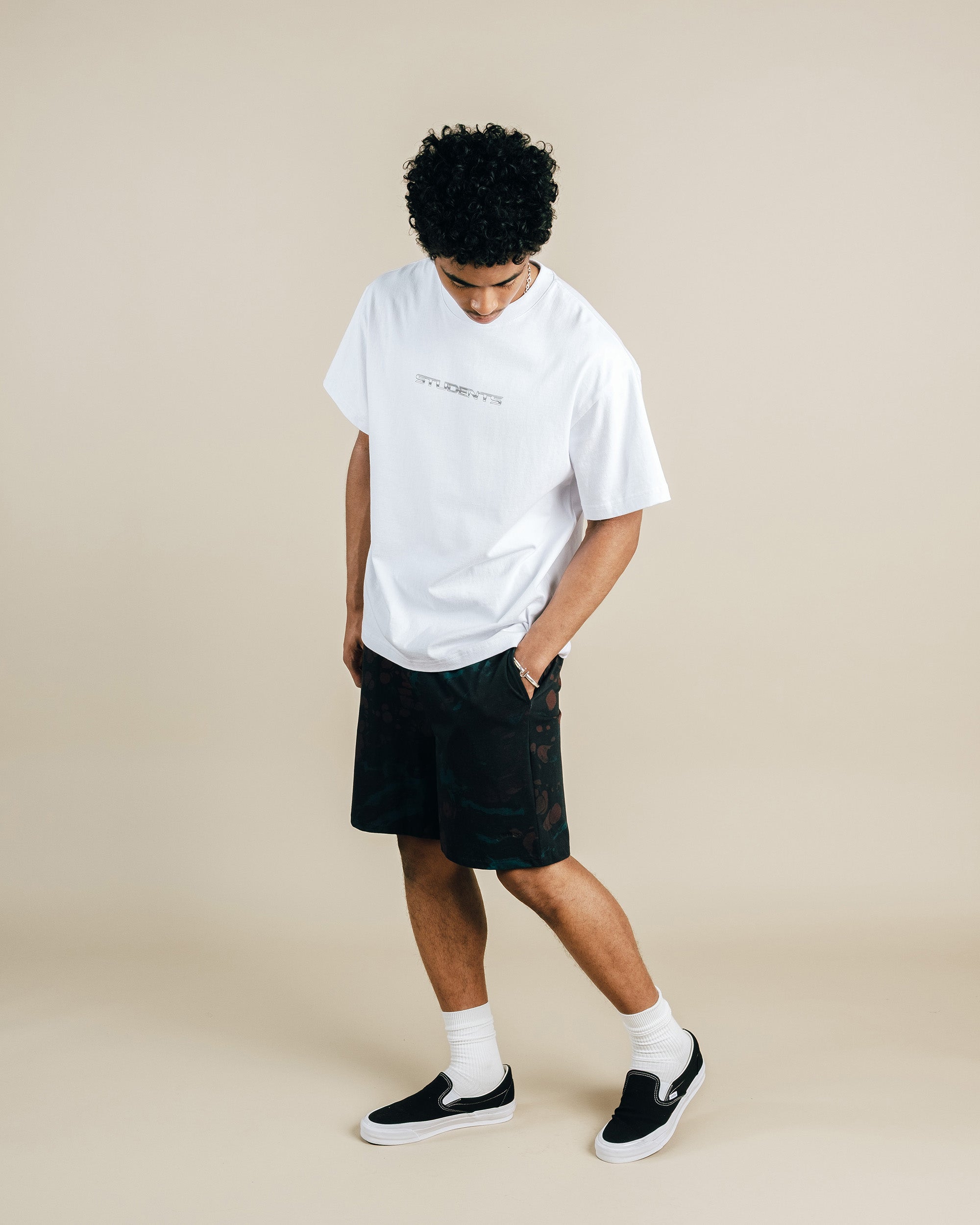 Person wearing a white t-shirt and black shorts on a beige background
