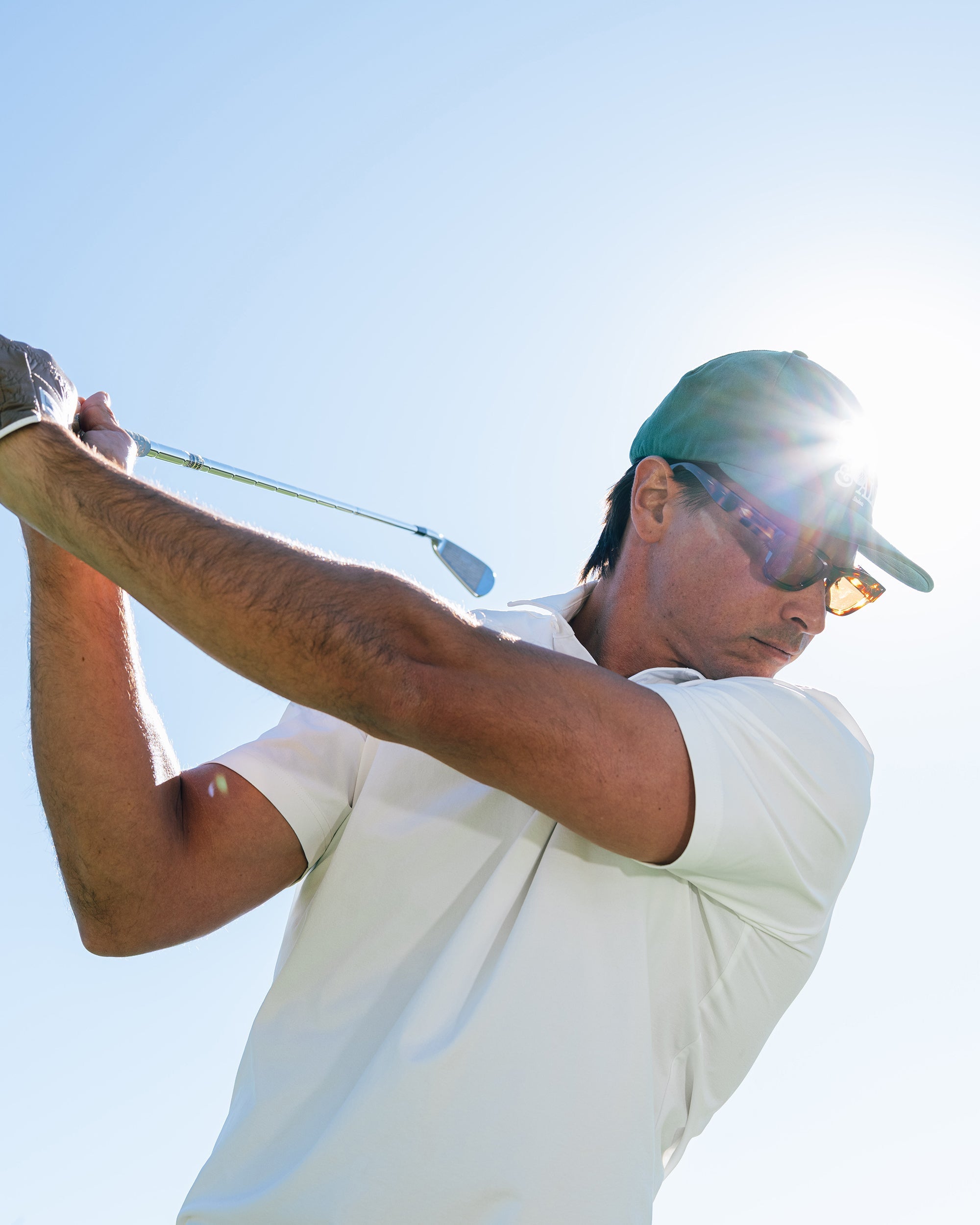 Man playing golf with a clear blue sky background