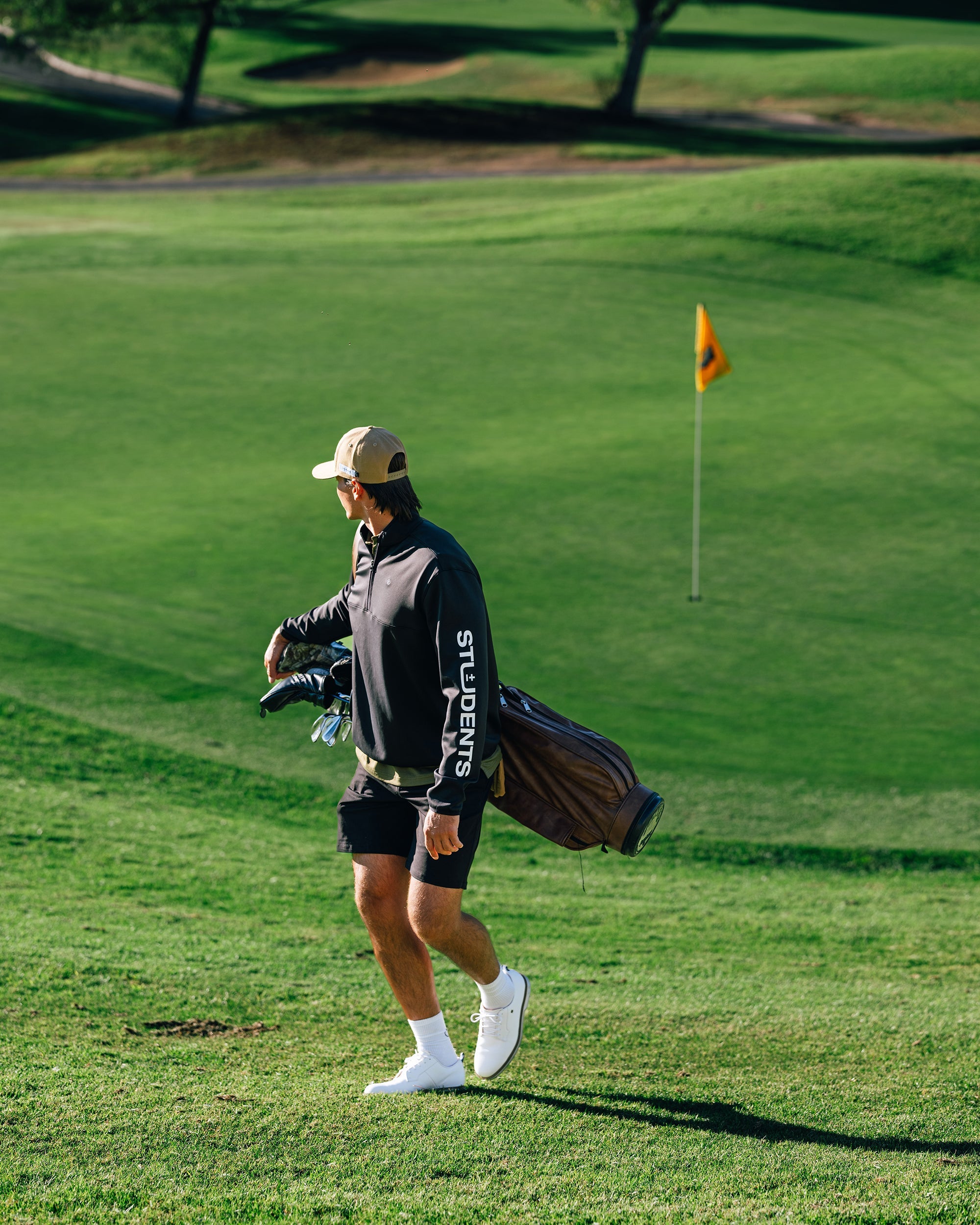 Golfer walking on a golf course with a caddie bag.
