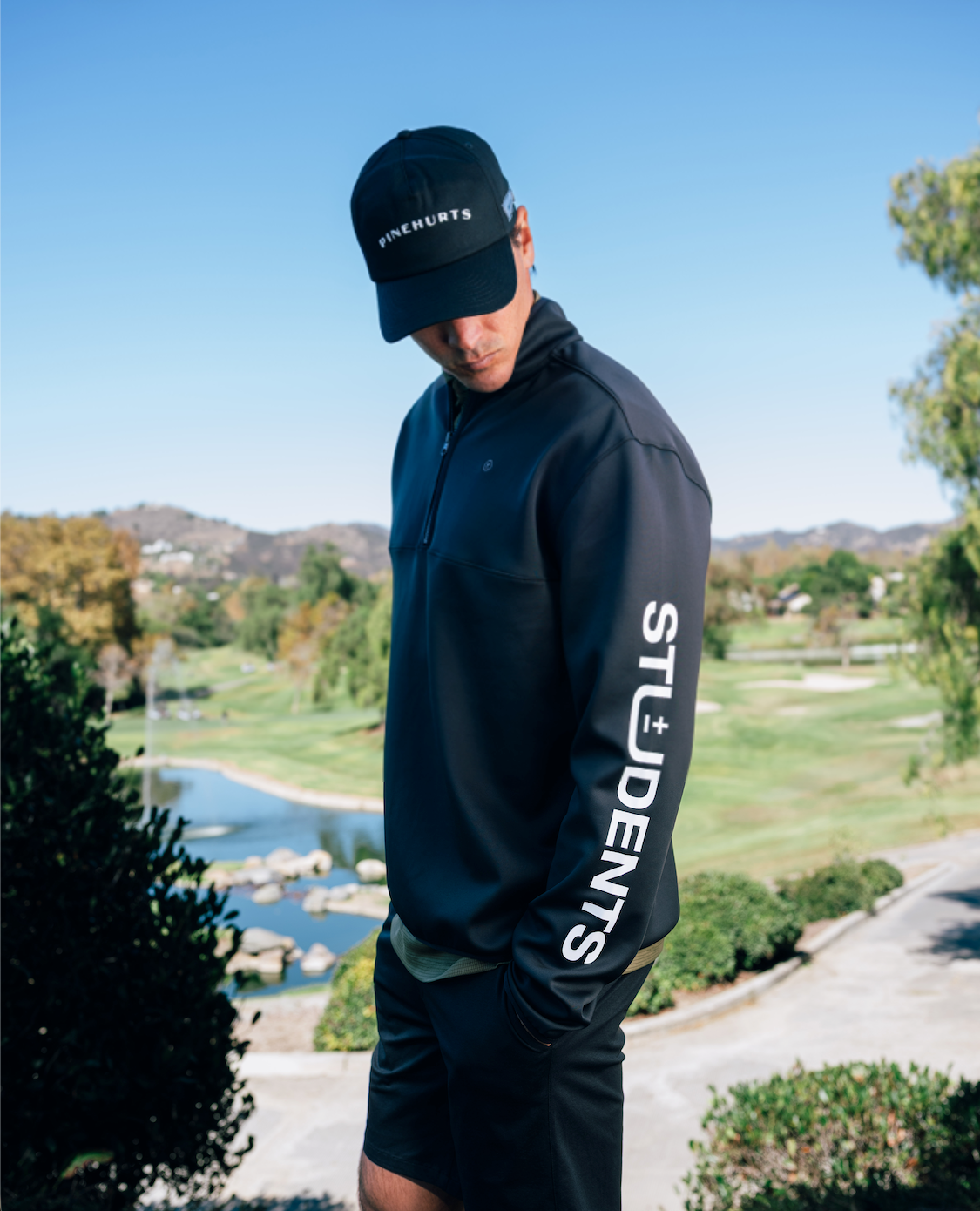 Person wearing a black jacket with 'STUDENTS' text, standing outdoors with a scenic background.