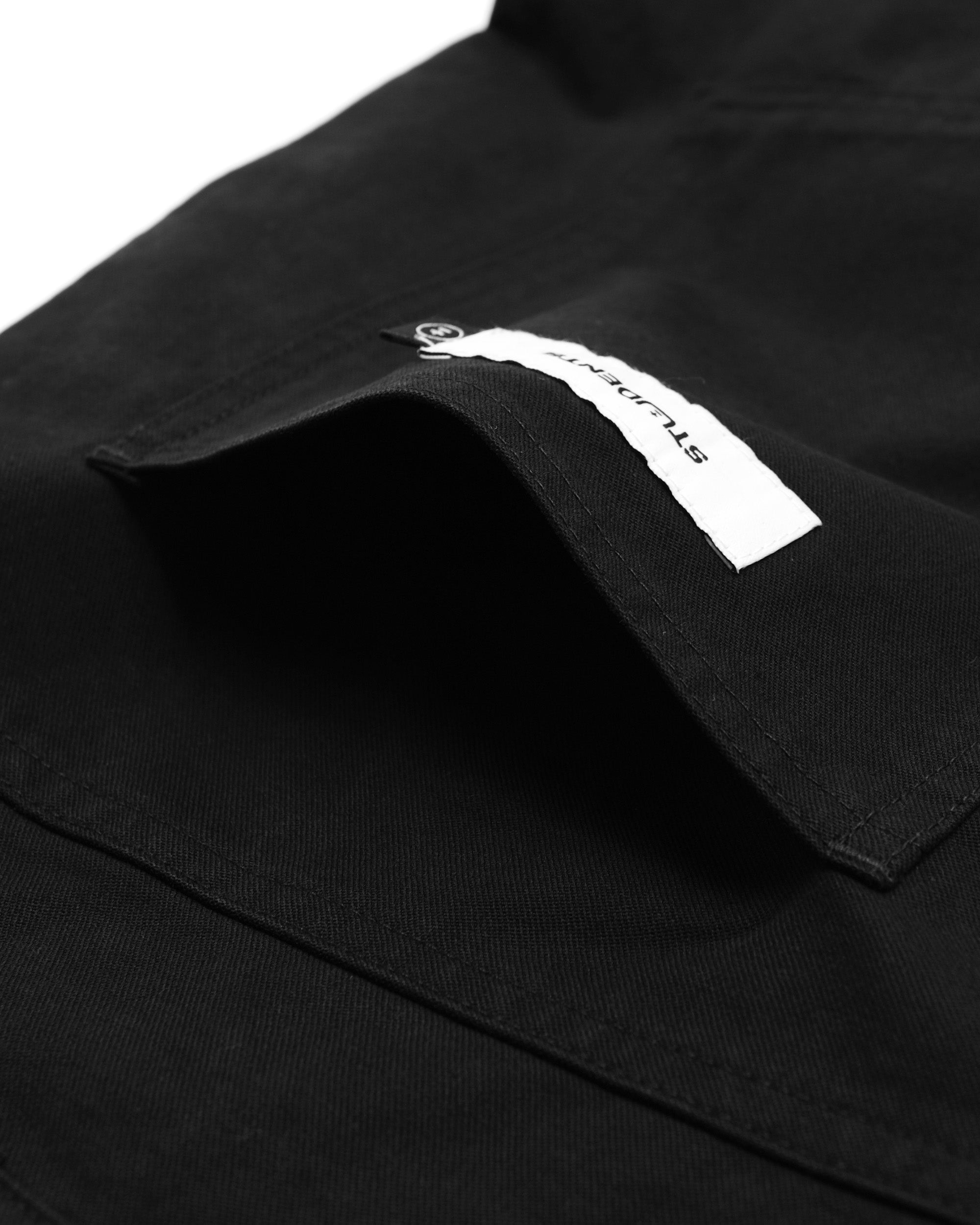 Close-up of a black pant
 with a brand label on the chest pocket.