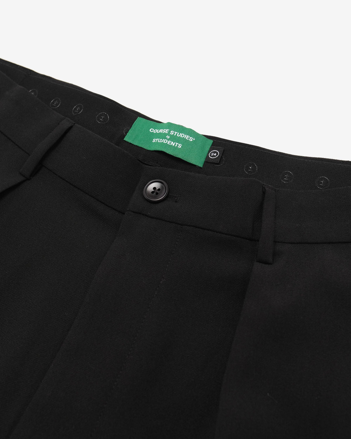 Close-up of black pants with a green tag on a white background