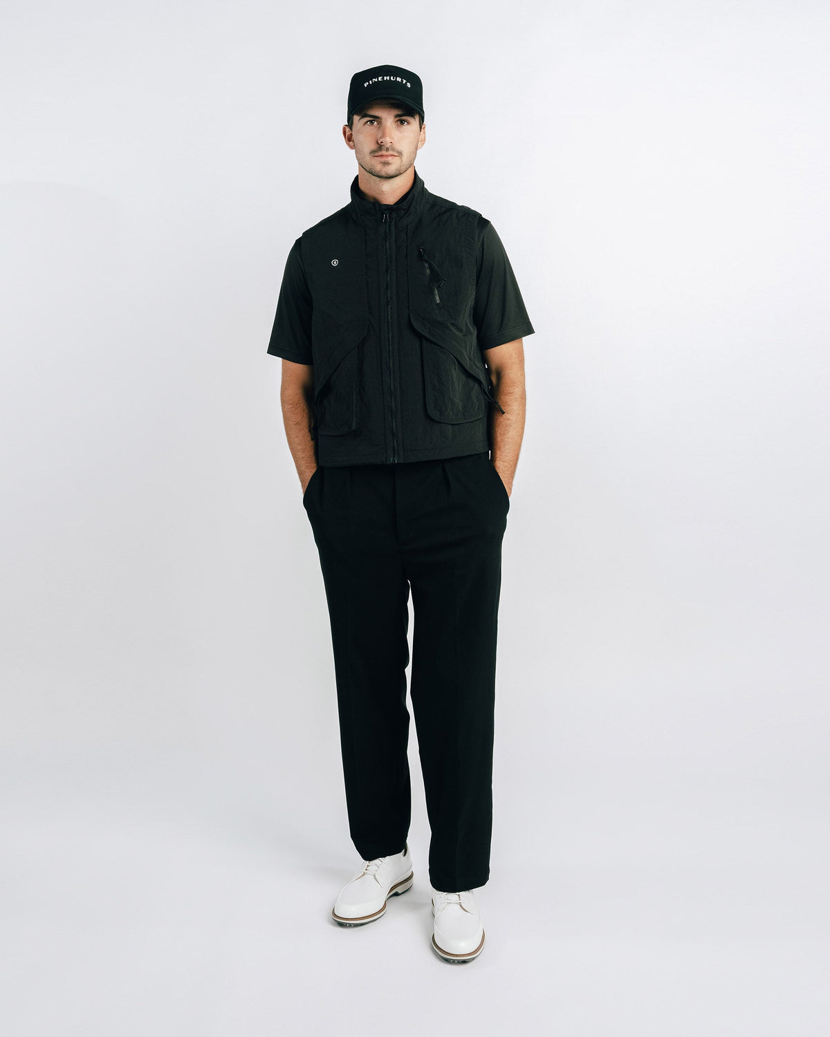 Man wearing a black outfit with a cap on a white background