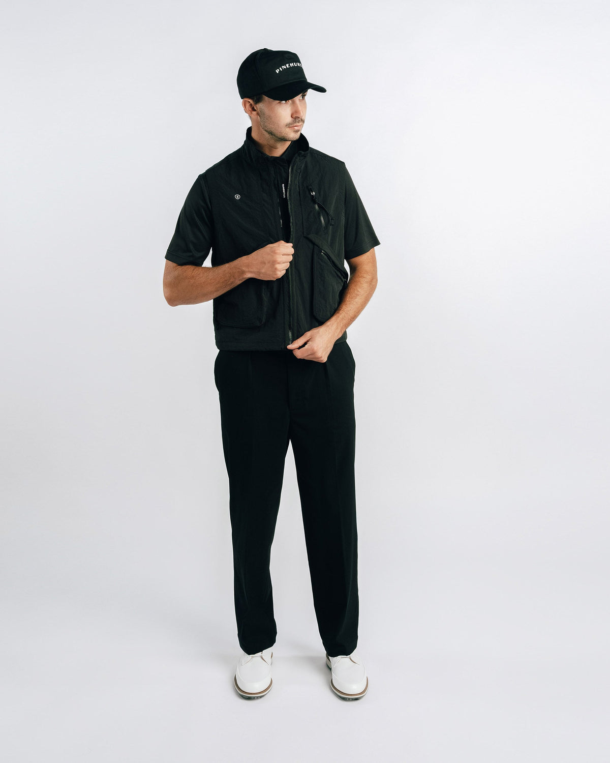 Man wearing a black outfit with a cap on a white background