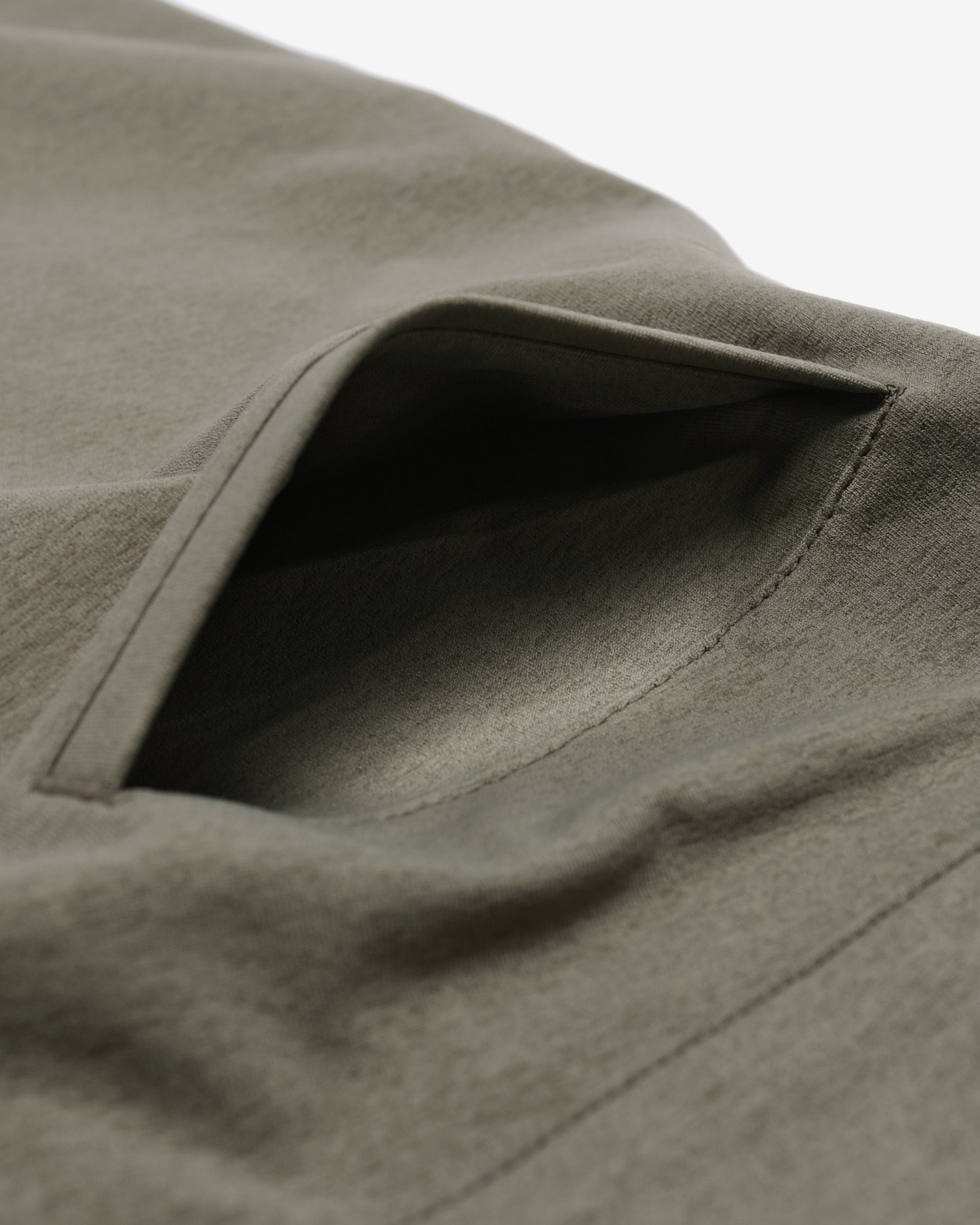 Close-up of a green fabric texture with a pocket detail.
