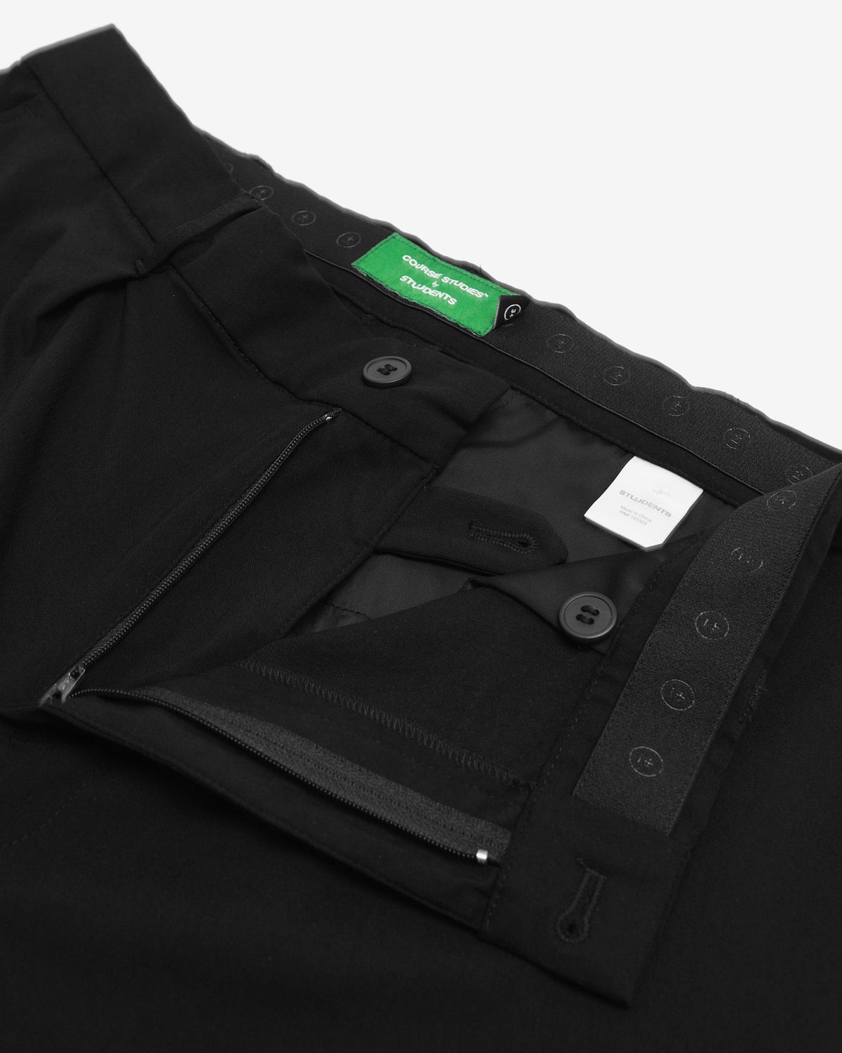 Close-up of black pants with a brand label on a white background