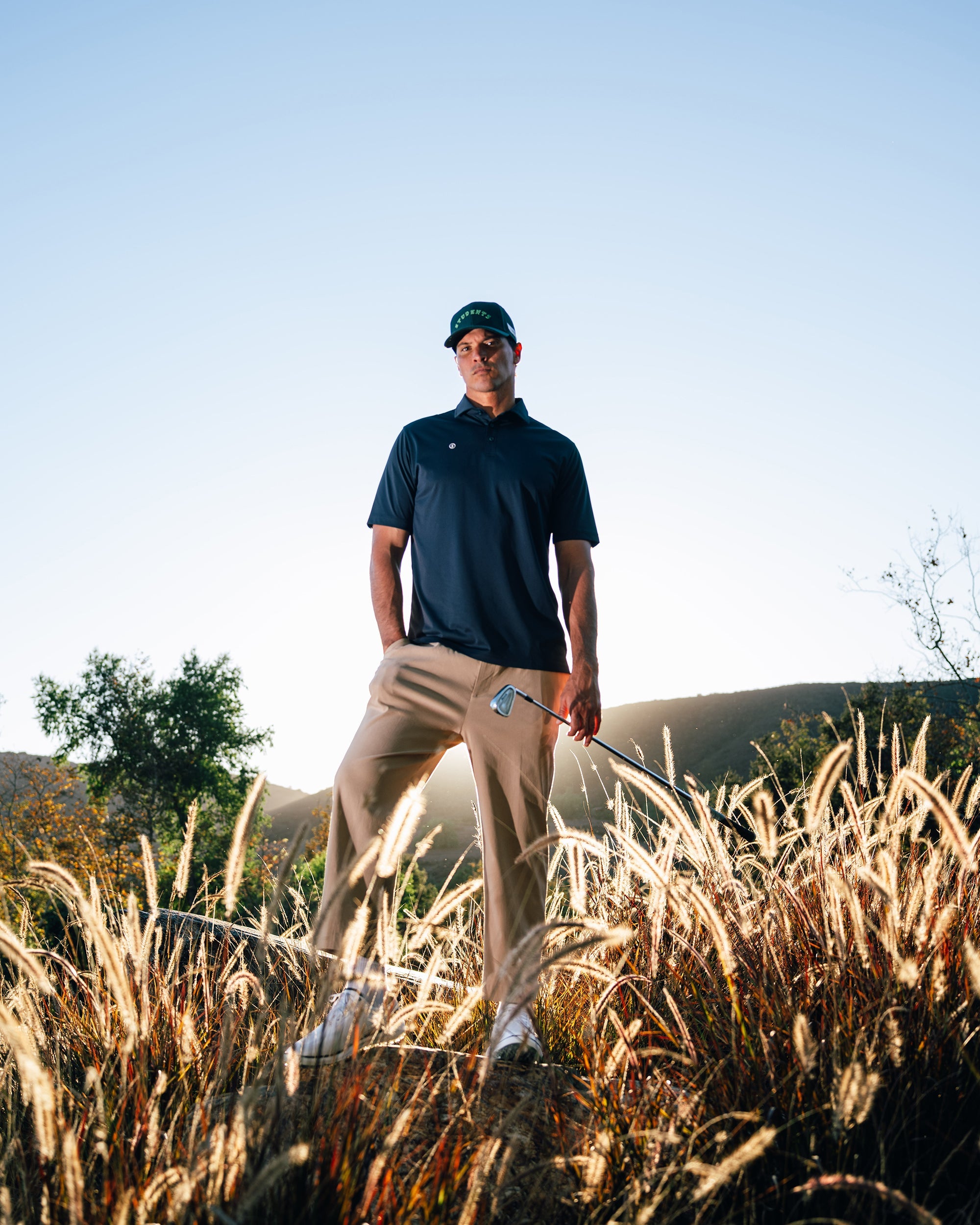 Man holding a golf club in a field with a clear sky