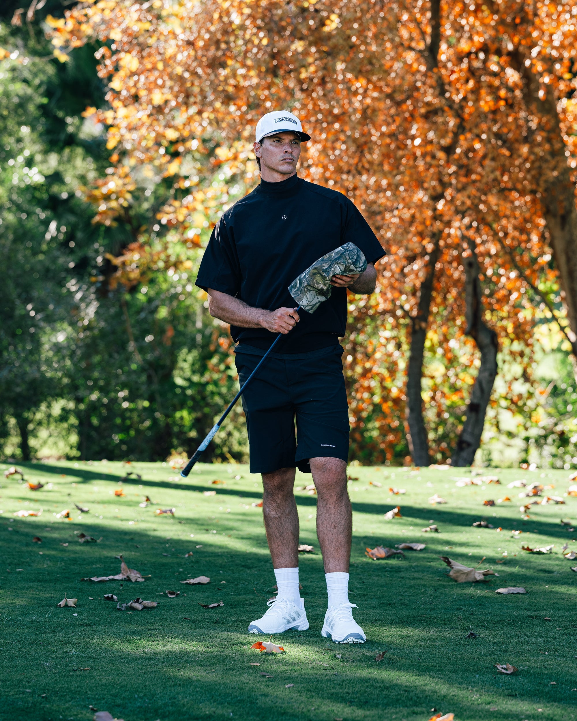 Man holding a golf club on a golf course with trees in the background