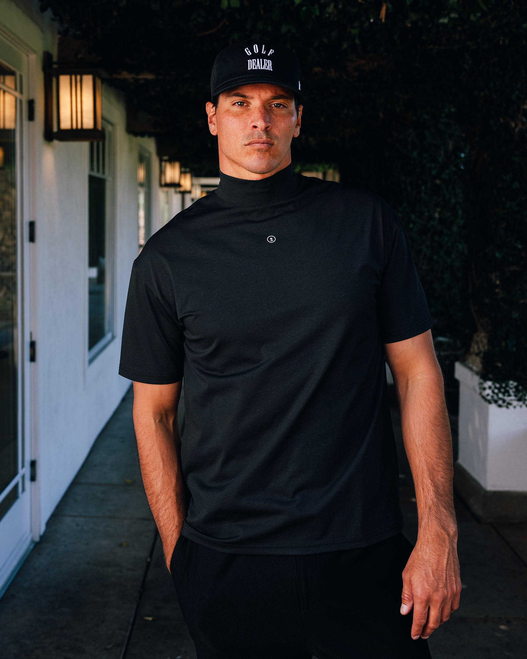 Man wearing a black turtleneck shirt and cap outdoors