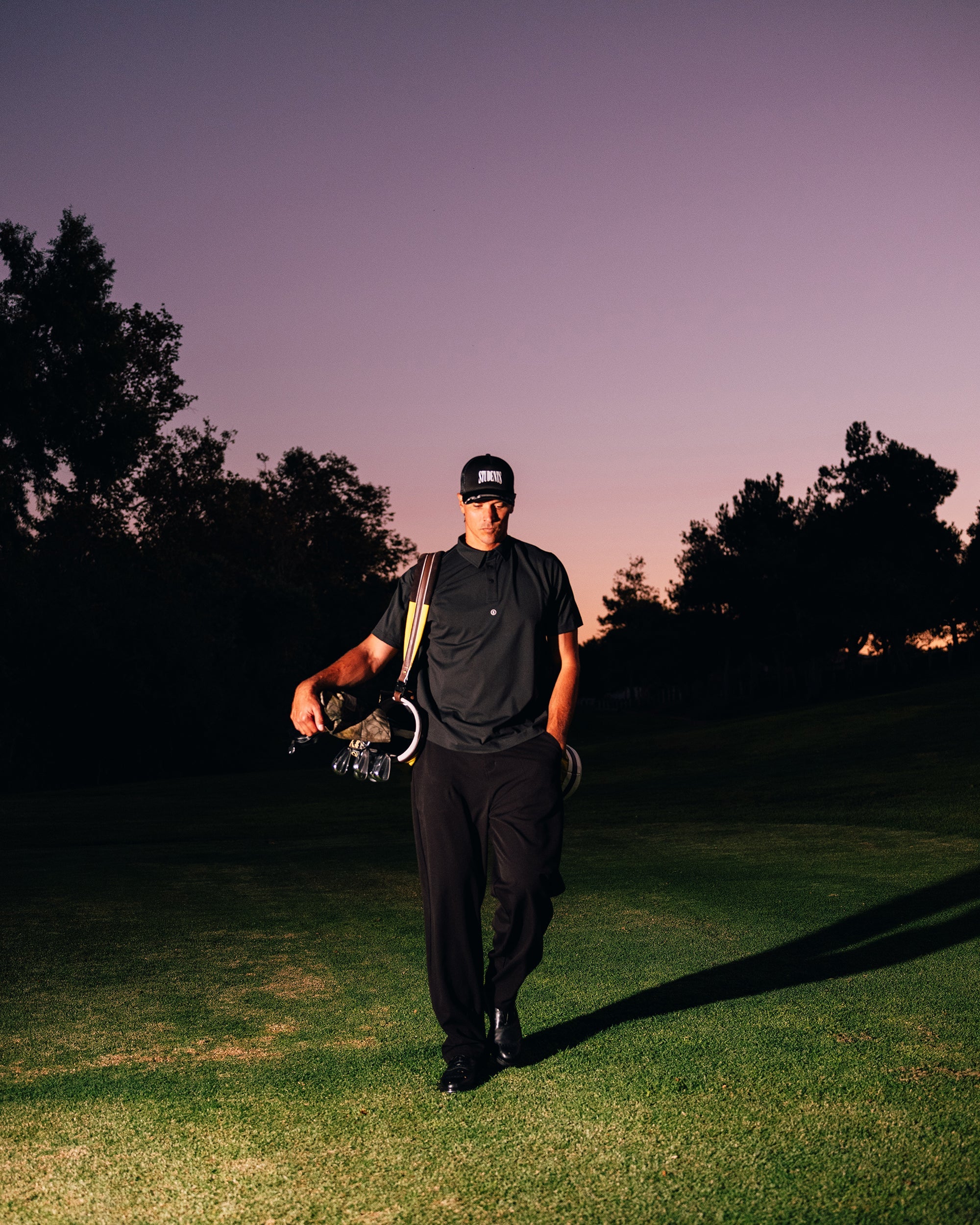 Person walking on a golf course with a purple sky